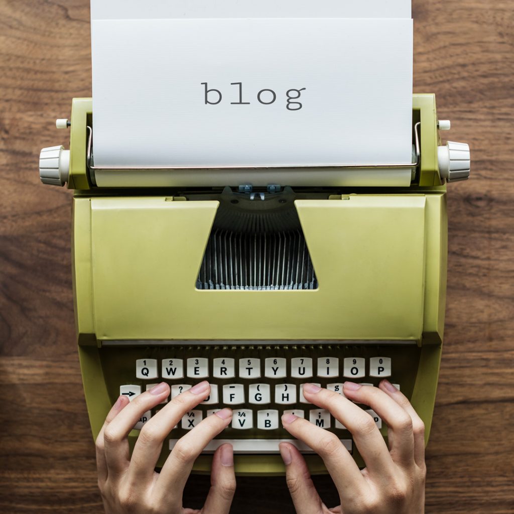 Persona che scrive con la macchina da scrivere la parola "blog"